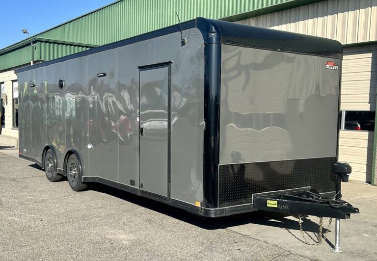 Large enclosed cargo trailer with a sleek gray body, black trim, black tandem wheels, side door, a black diamond-plate front panel, and a black hitch with safety chains