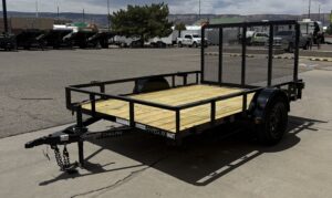 Open utility trailer with black fame and light wood flooring sitting in the lot at Pine Country.